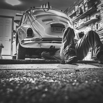 Zwart-wit foto van een automonteur die bezig is met een Volkswagen Kever. Zoals we bij Mackrad.nl graag WordPress websites onderhouden.