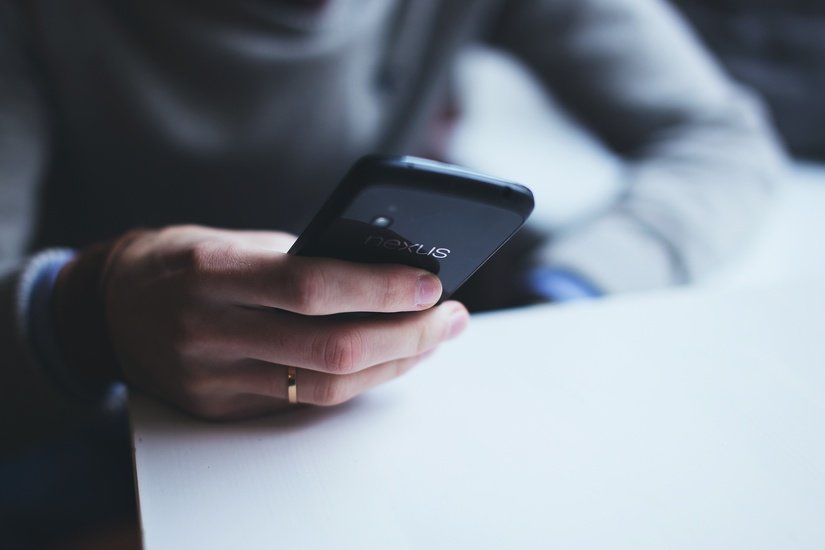 Foto van iemand met een telefoon in zijn/haar handen.