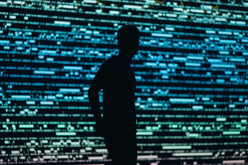 Rechtenvrijefoto van persoon voor verlichte muur door Chris Yang via Unsplash.